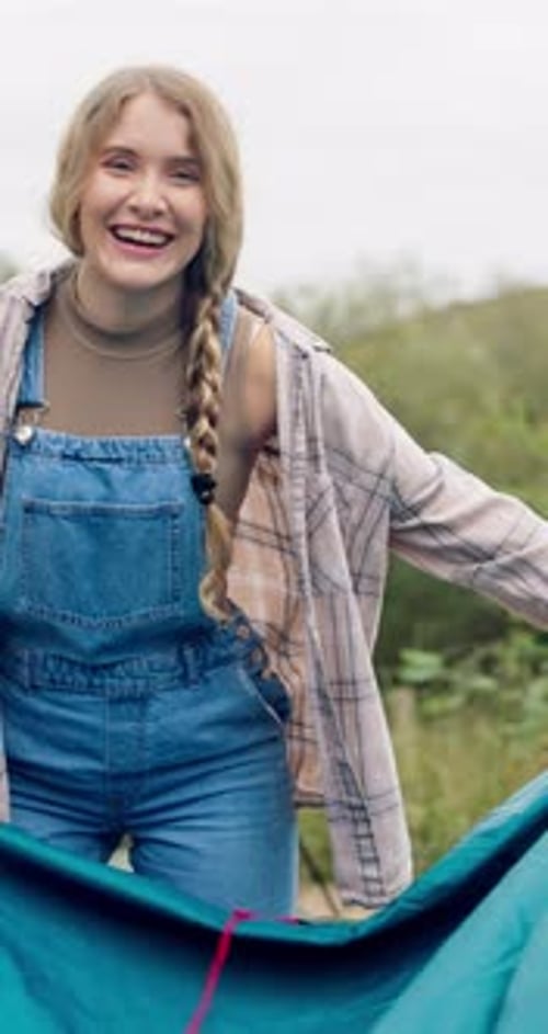 Smiling Woman Preparing Blue Tent in Green Field