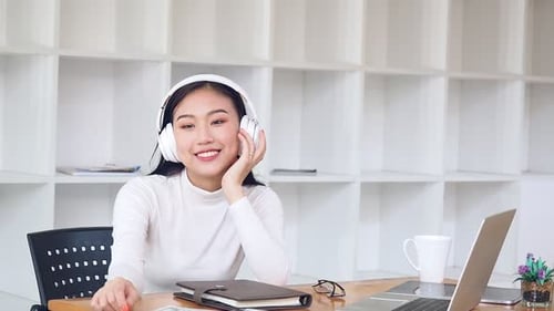 Smiling Woman with Headphones Sitting at Desk