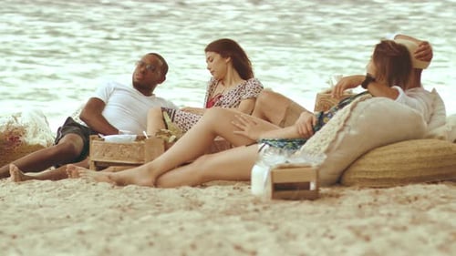 Millennial friends enjoy sunny picnic on sandy australian beach vacation