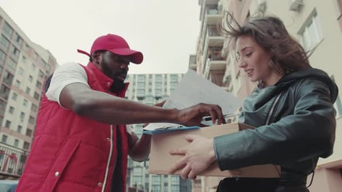 On Street Courier African American Gives a Parce to a Woman After Signing on Delivery Device
