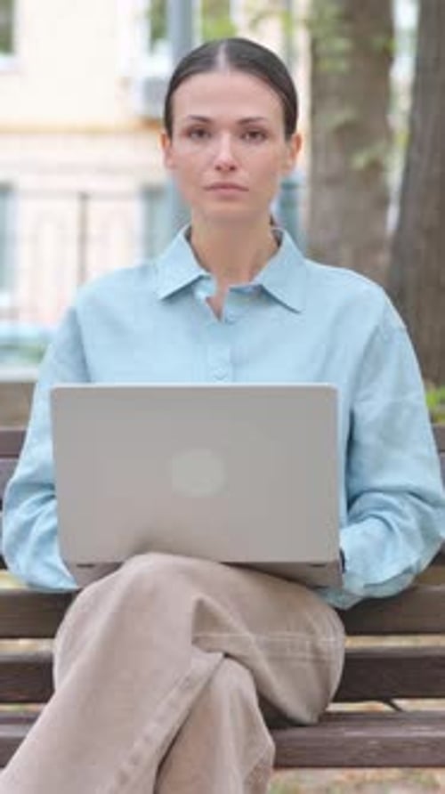 Woman Sitting on Bench Using Laptop in Park