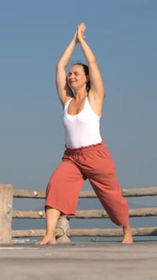 Woman Yoga Stretches Outdoors on Wooden Deck