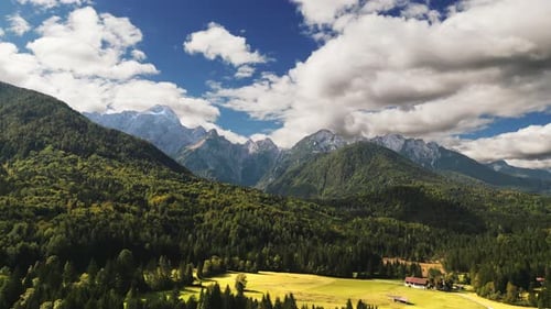Drone fotografado de um prado aberto em frente aos Alpes Julianos, Itália