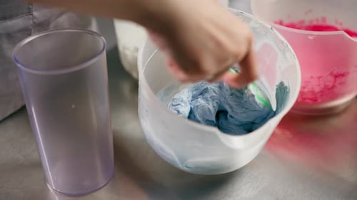 Closeup in a Professional Kitchen Baker Mixes Blue Cream in a Transparent Container