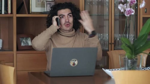 Young Adult Talking on Phone While Using Laptop