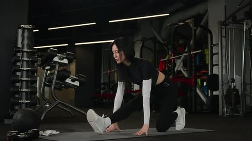 Athletic Woman Warming Up Stretching Legs in Gym