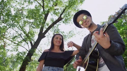 A happy couple connecting over music in a serene park