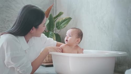 Caring Mother Giving Baby a Bath at Home