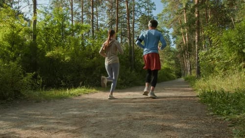 Young Man and Woman Jogging Together in Sunny Forest