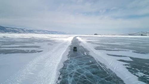 Aerial View on a Car Driving on an Ice Road on Frozen Baikal Winter Landscape of Lake Baikal