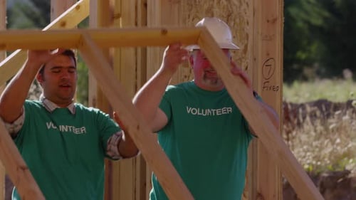 Volunteers Raising House Frame On Sunny Day