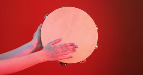 Tambourine Being Played With Hands On Red Background