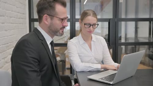 Two Business Colleagues Collaborating Using Laptop in Office