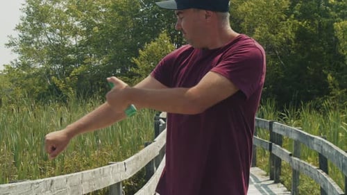 Lake Day Essentials Man Sprays Mosquito Repellent in Sunshine