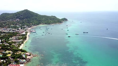 Shoreline aerial view. Tropical island overgrown by rainforest. Beach with white sand. Camera moves