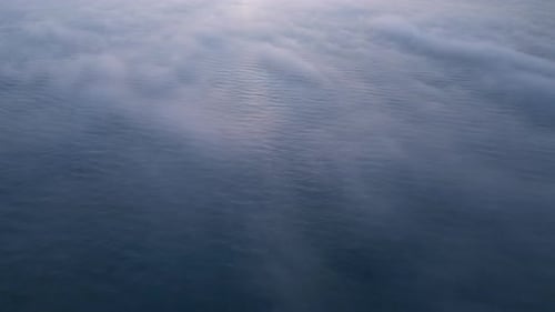 Aerial View of a Sunrise Sea with a Blanket of Morning Fog and Morning Sunbeams Shining Through
