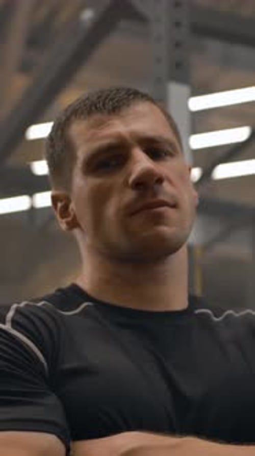 Adult Man Stands Confidently in Gym with Arms Crossed