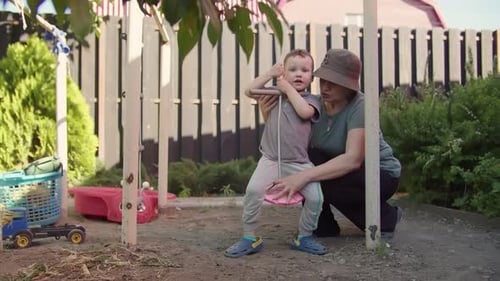 Femme apprenant à un enfant à se balancer sur une balançoire de jardin faite maison