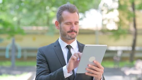 Adult Man Uses Tablet Outdoors in Urban Setting