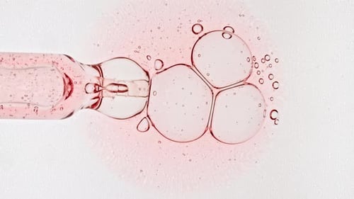Groupe de bulles transparent dans des cellules de pipette au microscope, gel cosmétique liquide avec molécule