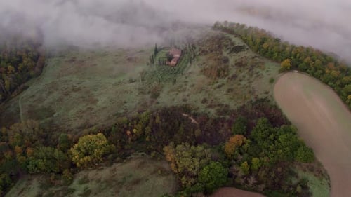 Aerial view of foggy countryside with villa and cypress trees, Italy.