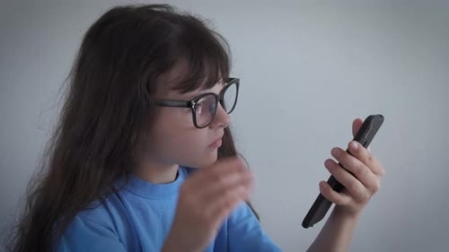 Child Looking at Smartphone with Glasses Indoors
