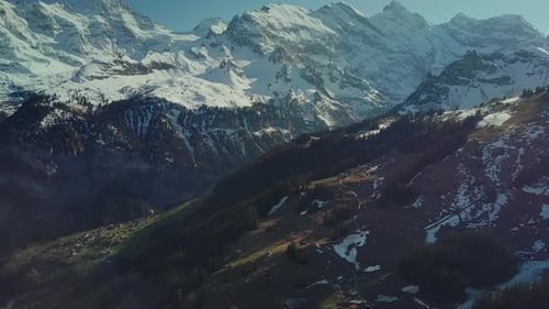 Panorâmica aérea das montanhas nevadas dos Alpes suíços até a vila alpina