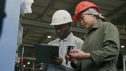 Engineer and Supervisor Measuring Machine Details with Caliper for Report