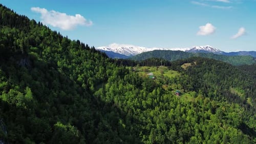 Beautiful Aerial Background Of Nature And Mountain Lodges. Green Mountains With Snowy Peaks