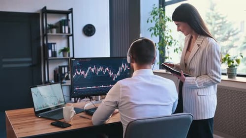 Analyzing the graphs. Man and woman are working together by computer in the office.