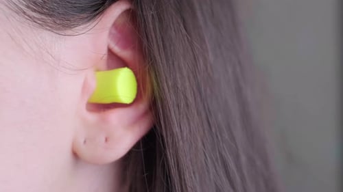 Woman wearing earplugs made from safe, recyclable materials for noise reduction and comfort.