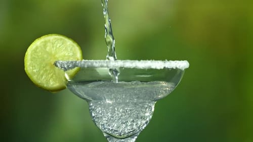 Pouring Refreshing Drink into Margarita Glass with Lime