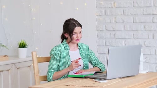 Woman Sitting at a Table Working at a Laptop Computer Concept of Remote Work From Home Home Office