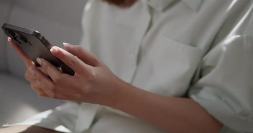 A woman engages with her smartphone in a comfortable home setting.
