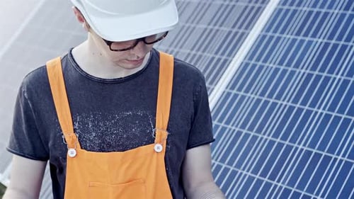 Portrait of a Worker in Glasses and a Helmet That Sets Sun Panels on a Summer Evening