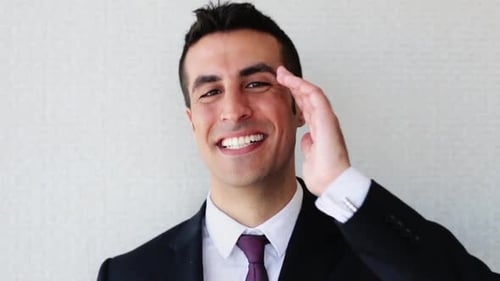 Happy smiling businessman touches hair in modern office environment