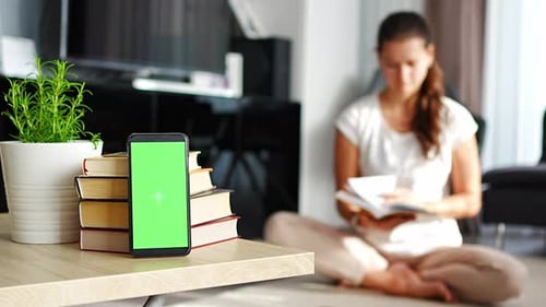 Digitales Detox-Konzept-Foto-Smartphone mit grünem Chroma-Key-Bildschirm und Lesebuch für Frauen in der