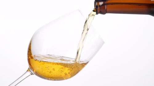 Close Up Of Wine Being Poured Into A Glass On The Light White Screen Background In The Studio
