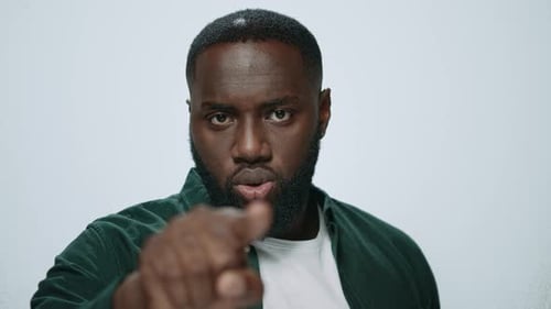 Retrato de hombre afroamericano señalando con el dedo sobre fondo claro. Hombre ambicioso de cerca