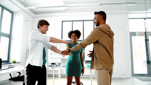 Happy multiethnic business team stacking hands in modern office for success