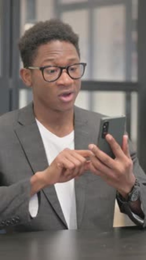 Vertical, African American Man Celebrating Success on Phone in Office