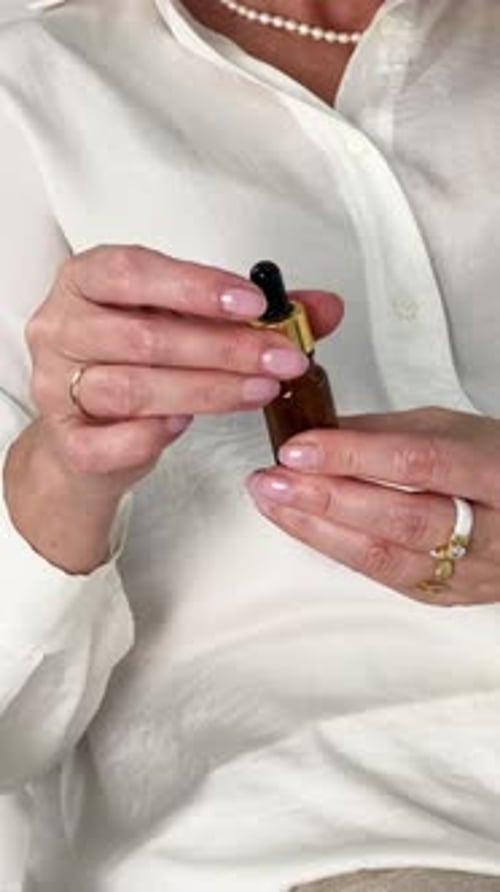 Woman Holding and Opening Bottle of Essential Oil