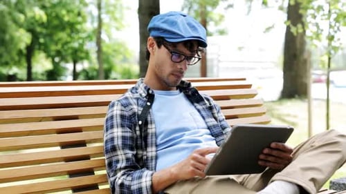 Man on Bench Using Tablet in Sunny Park