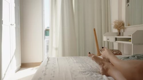 Woman's Feet Relaxing on Bed in Bright Bedroom