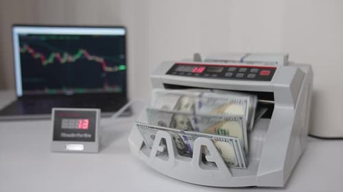 Little money counting machine turning money. Laptop with a black screen and a curve
