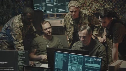Five Adults Analyze Monitors in a Dark Command Center