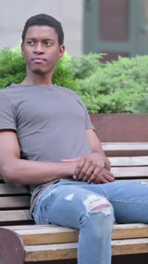 Pensive Young Young African Man Sitting on Bench and Thinking, vertical video