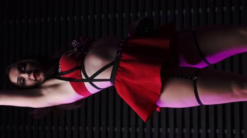 Portrait of a beautiful girl in a red skirt and bra, leather belts dancing against the background of