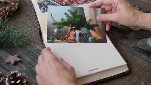 Manos femeninas colocan una foto de Navidad impresa en un álbum de fotos