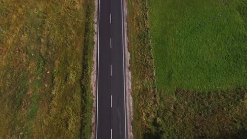 Luftaufnahme über einer langen kurvigen Bergstraße inmitten von dichtem Grün mit Sonnenstrahlen